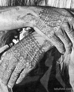 Фото тату: Черная племенная татуировка, покрывающая руку. Изображение состоит из абстрактных узоров и спиралей.