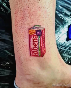 Фото тату: реалистичное изображение коробки сока Ribena на ноге.