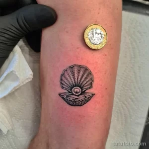 Фото тату: черно-белое изображение раковины в минималистичном стиле на предплечье.