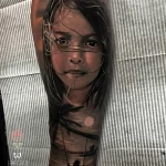 Фото тату реалистичного портрета девочки с длинными волосами на руке. Детализированный рисунок с мягкими тенями и выразительным взглядом.