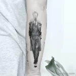 Фото тату на руке: оригинальное изображение человека в костюме с лампочкой вместо головы, выполненное в черно-белой графике.