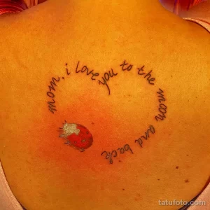 Фото тату с изображением красной клубники и надписью "mom, i love you to the moon and back" на спине. Нежный и трогательный рисунок татуировки.