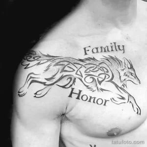 Фото татуировки волка в стиле трайбл на груди с надписями 'Family' и 'Honor'. Черные узоры и линии создают мощный и символичный образ.