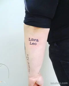 Фотография простой татуировки на руке, изображающей названия знаков зодиака Libra и Leo, выполненной черным цветом.
