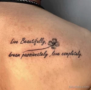 Фото тату с надписью 'Live Beautifully, dream passionately, love completely' и маленькой розочкой на спине девушки.