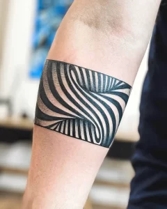 Фото тату: браслет на предплечье, создающий эффект оптической иллюзии с помощью черно-белых полос. Современный и необычный дизайн.