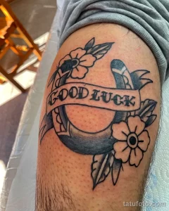 Фото тату подковы с надписью "Good Luck", выполненное в стиле олдскул на руке. Классический рисунок татуировки, символизирующий удачу и позитив.