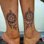 Фото парных татуировок на лодыжках, изображающих одинаковые мандалы с растительными элементами. Черно-белый дизайн, детализированная проработка.