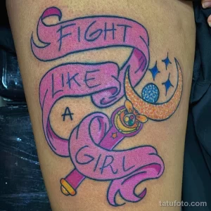 Фото яркой татуировки с надписью "Fight Like a Girl" и сердцем на руке. Необычный дизайн, яркие цвета, вдохновляющий рисунок.