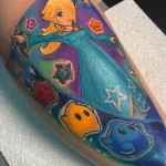 Фото тату принцессы Пич из Super Mario на ноге. Яркие цвета, мультяшный стиль, детализированный рисунок татуировки.