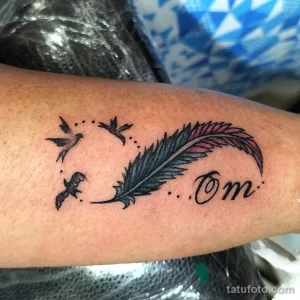 Фото татуировки на руке с изображением пера, трех птиц и символа 'Om'. Минималистичный стиль, черные линии.