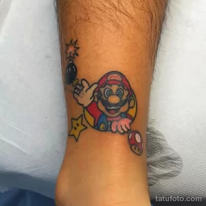Фото тату на ноге с изображением Марио из игры Super Mario. Яркий и красочный рисунок татуировки в стиле ретро.