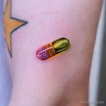 Фото тату маленькой капсулы с психоделическим узором внутри, выполненной в ярких цветах на руке. Простой дизайн и яркие цвета.
