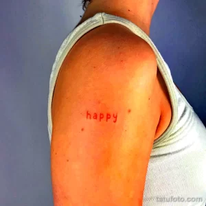 Фото тату: татуировка с надписью "happy" на плече. Красные контуры, минималистичный стиль, позитивный дизайн.