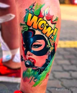 Фото тату на предплечье: девушка в маске супергероя с надписью 'WOW!' в стиле комиксов, яркие брызги краски.