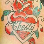 Фото тату на плече: красная роза в форме сердца с надписью 'Chesty'. Изящный рисунок татуировки для девушек, выполненный в традиционном стиле.