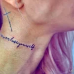 Фото тату с надписью "never lose yourself" и небольшим крестом на затылке. Элегантная татуировка, выполненная каллиграфическим шрифтом.