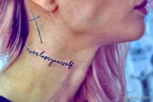 Фото тату с надписью "never lose yourself" и небольшим крестом на затылке. Элегантная татуировка, выполненная каллиграфическим шрифтом.