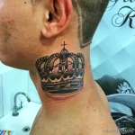 Фотография татуировки короны с крестом на задней части шеи. Черно-белый рисунок татуировки с детальной проработкой.