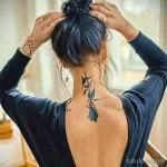 Фото тату: Изящная татуировка ветки с цветами, спускающаяся по шее и спине девушки. Нежный и романтичный рисунок татуировки.