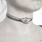 Черно-белое фото тату змеи, обвивающей шею девушки. Минималистичный рисунок татуировки с четкими линиями и реалистичной головой змеи.