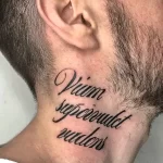 Фото тату латинской фразы 'Vitam Sepcoundet Audens' на шее. Черный контур, каллиграфический шрифт, элегантный стиль. Подходит для тех, кто ценит мудрость и смелость.