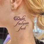 Фото тату латинской фразы 'Dolor Fortior Fecit' на шее. Изящный шрифт, фиолетовые оттенки, женственный стиль. Подходит для тех, кто ценит мудрость и силу духа.