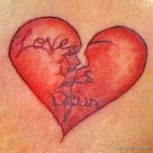 Фото тату на коже: разбитое сердце с надписью 'Love is Pain'. Простой и лаконичный рисунок татуировки.