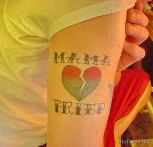 Фото тату на руке: разбитое сердце с надписями 'MAMA' и 'FREED'. Простой рисунок татуировки, символизирующий потерю и освобождение.