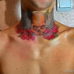 Фото тату черепа с розами на шее мужчины. Рисунок выполнен в ярких цветах с использованием реалистичной прорисовки деталей.