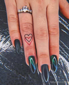 Фото тату: три маленьких сердца, нарисованных контуром на пальце руки. Нежные татуировки, выполненные красными чернилами, символизируют любовь и связь.