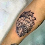 Фото татуировки на руке в стиле blackwork: сердце, из которого вырывается осьминог. Детализированный черно-белый рисунок.