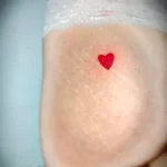Фото тату маленького красного сердца на запястье. Простой и минималистичный рисунок татуировки в ярком цвете.
