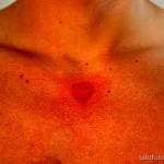Фото тату на груди с изображением двух маленьких сердец, выполненных в нежной цветовой гамме. Рисунок татуировки в стиле акварель.