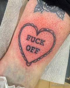 Фото тату на руке: сердце, внутри которого надпись 'FUCK OFF', выполненное в черно-белом цвете с четкими контурами.