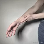 Фото тату на запястье: маленькое, черное сердце, выполненное в минималистичном стиле. Простой и элегантный рисунок татуировки.