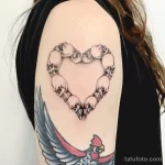 Фото тату на плече: сердце, составленное из черепов, выполненное в технике blackwork. Детализированный рисунок татуировки с четкими контурами.