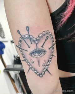 Фото тату: черно-белая татуировка в стиле blackwork на руке. Изображено сердце, пронзенное булавками, с каплями слез.