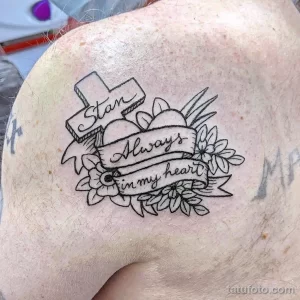 Фото тату на плече: изображение штата Техас с надписью 'Stan Always in my heart', обрамленное цветами и лентой.