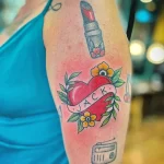 Фото татуировки на плече: красочное изображение сердца с надписью 'JACK', помады и кассеты, выполненное в стиле олд скул.