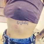 Фото тату: татуировка надписи "Crybaby" в готическом стиле с маленьким сердцем. Черно-белая татуировка на теле.