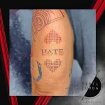 Фото татуировки в стиле кросс-стич с изображением сердца и надписью 'HATE'. Необычный и оригинальный рисунок.