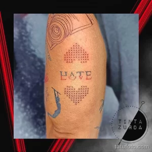Фото татуировки в стиле кросс-стич с изображением сердца и надписью 'HATE'. Необычный и оригинальный рисунок.