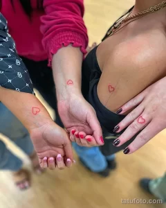 Фото парных татуировок на запястьях: два небольших красных сердца. Минималистичный дизайн и яркий цвет.