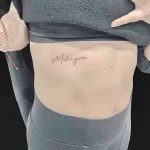 Фото тату: Минималистичная татуировка с надписью имени "Milagro", выполненная изящным шрифтом на боку.