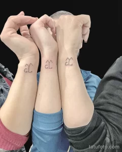 Фото тату на запястьях: три одинаковых татуировки с изображением стилизованного домика, выполненные в минималистичном стиле черными чернилами.