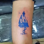 Фото тату на руке: яркий рисунок домика с голубой крышей и летящими птицами, выполненный в наивном стиле. Оригинальный и запоминающийся рисунок татуировки.