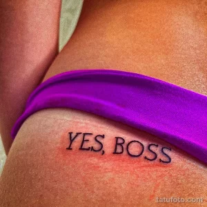 Фото тату надписи 'Yes, Boss' черным цветом, выполненной на боку под грудью. Простой и лаконичный рисунок татуировки.
