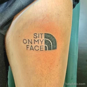 Фото тату на руке с надписью "SIT ON MY FACE" и логотипом The North Face. Оригинальный и юмористический рисунок татуировки.