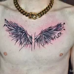 Фото тату: Большая татуировка черных крыльев с надписью 'FUCK' на груди мужчины.